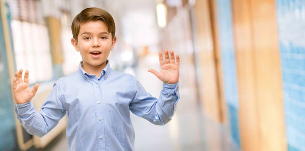 Όμορφος νήπιο παιδί με πράσινα μάτια, ευτυχισμένη και έκπληκτος επευφημίες εκφράζοντας wow χειρονομία στο διάδρομο του σχολείου - Φωτογραφία, εικόνα