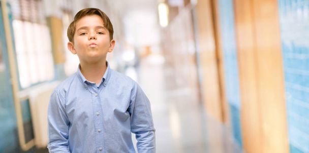 Niño guapo con ojos verdes expresando amor, golpes beso en la cámara, coqueteando en el pasillo de la escuela
 - Foto, imagen
