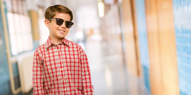 Όμορφος νήπιο παιδί με πράσινα μάτια, αυτοπεποίθηση και χαρούμενοι με ένα μεγάλο φυσικό χαμόγελο γελώντας στο διάδρομο του σχολείου - Φωτογραφία, εικόνα