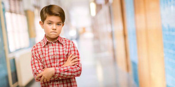 Pěkný batole dítě s zelené oči nervózní a vystrašený kousání rtů pohledu kamery s netrpělivým výrazem, zamyšlený na školní chodbě - Fotografie, Obrázek