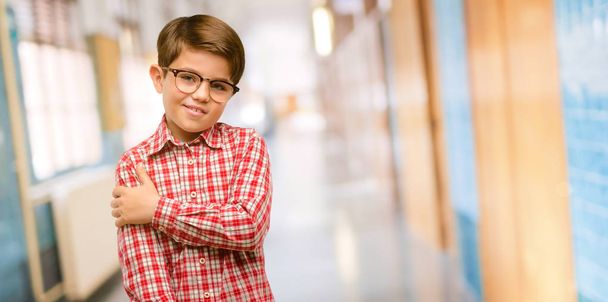 Niño guapo con ojos verdes confiado y feliz con una gran sonrisa natural riendo, expresión natural en el pasillo de la escuela
 - Foto, Imagen