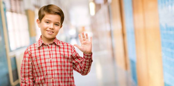 Handsome toddler child with green eyes raising finger, is the number five at school corridor - Photo, Image