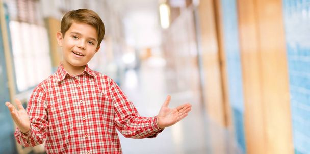 Criança bonita com olhos verdes confiante e feliz com um grande sorriso natural gesto de boas-vindas no corredor da escola
 - Foto, Imagem