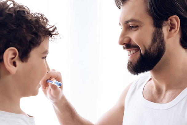 Happy father brushes teeth of young son with toothbrush. - Zdjęcie, obraz