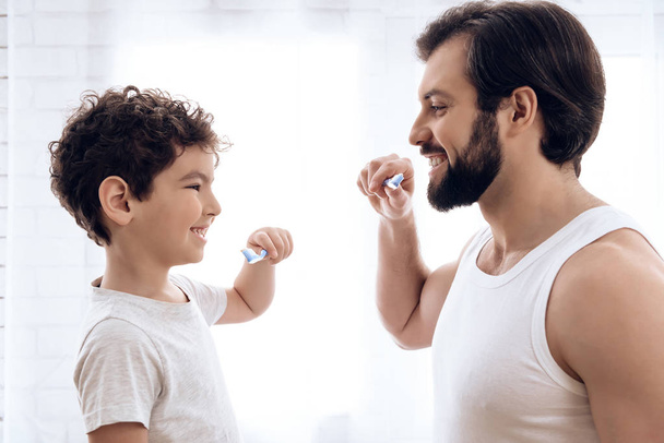 Happy father and son brush teeth, looking at each other. - Photo, Image