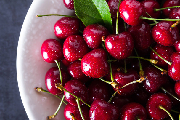 Fresh red ripe cherries on white plate - Foto, Imagen