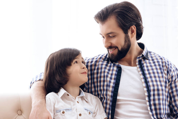 Bearded father communicates with teenage son sitting on couch. - Valokuva, kuva