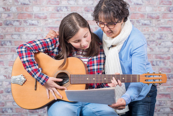 молодий підліток вчиться грати на гітарі зі своїм вчителем
 - Фото, зображення