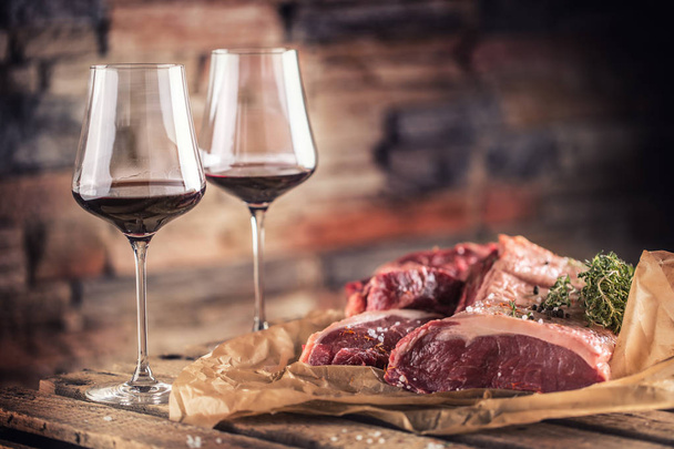 Two cups with red wine and raw beef steak on wooden table - Foto, Imagen