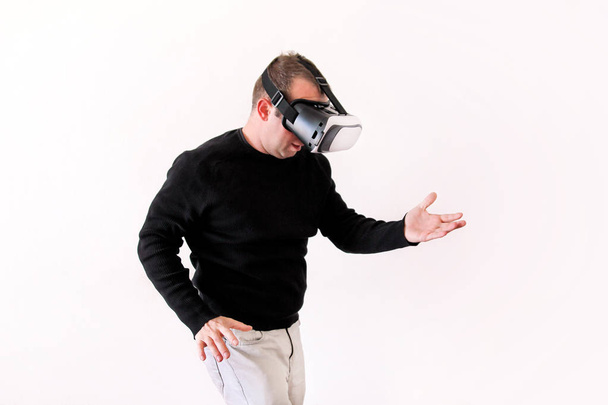 Man wearing and playing mobile game app on device virtual reality glasses on white background. Business man at office action and using in virtual headset box. Contemporary technology concept. - Foto, Imagem