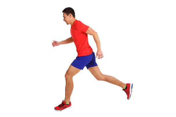 Full length side portrait of fit older asian man running over white background - Photo, Image