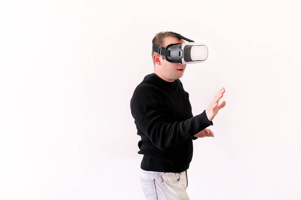 Man wearing and playing mobile game app on device virtual reality glasses on white background. Business man at office action and using in virtual headset box. Contemporary technology concept. - Photo, Image