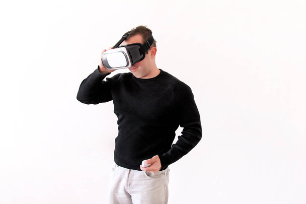 Man wearing and playing mobile game app on device virtual reality glasses on white background. Business man at office action and using in virtual headset box. Contemporary technology concept. - Photo, Image