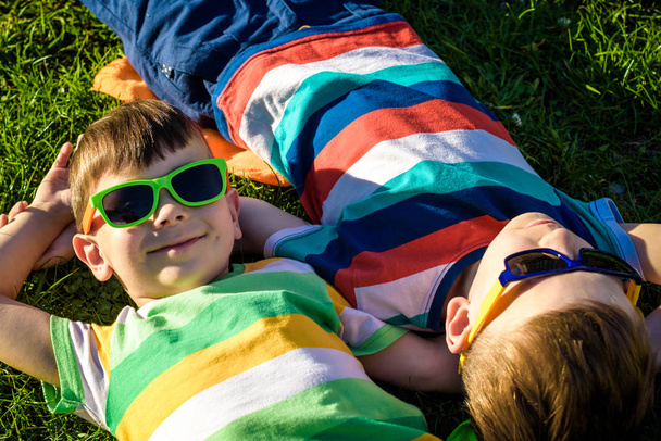 Heureux enfants souriants joyeux, allongés sur une herbe, portant chanté
 - Photo, image