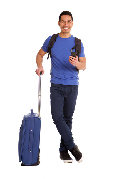 Full length portrait of handsome mid adult asian man standing with suitcase and mobile phone over white background - Foto, Imagem