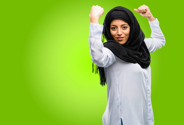 Mladá arabská žena nosí hidžáb ukazující biceps vyjadřující sílu a tělocvičně koncept, zdravý život jeho dobré - Fotografie, Obrázek