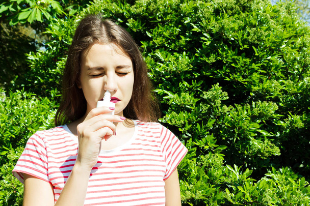Fiatal gyönyörű nő segítségével orr spray-a parkban - Fotó, kép
