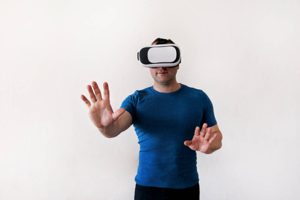 Mies yllään ja pelaa mobiilipelisovellusta laitteessa virtuaalitodellisuus lasit valkoisella taustalla. Mies toiminta ja käyttämällä virtuaalinen kuulokkeet, VR laatikko käytettäväksi älypuhelimen. Nykyteknologian käsite
 - Valokuva, kuva