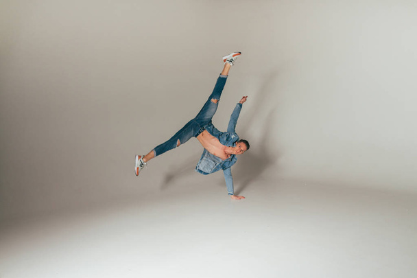 shot of jump feet up, of mad, crazy, cheerful, successful, lucky guy in casual outfit, jeans, jumping with hands up,triumphant, gesturing against white background - 写真・画像