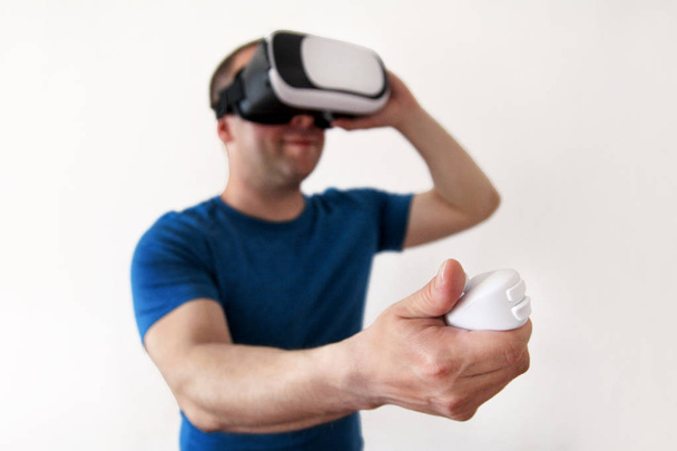 Man wearing and playing mobile game app on device virtual reality glasses on white background. Man action and using in virtual headset, VR box for use with smart phone. Contemporary technology concept - Photo, Image