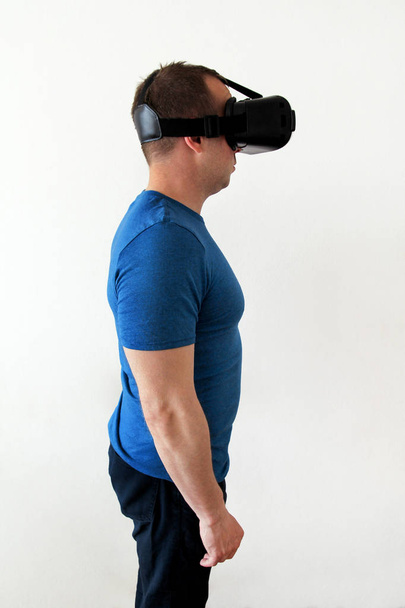 Man wearing and playing mobile game app on device virtual reality glasses on white background. Man action and using in virtual headset, VR box for use with smart phone. Contemporary technology concept - Φωτογραφία, εικόνα