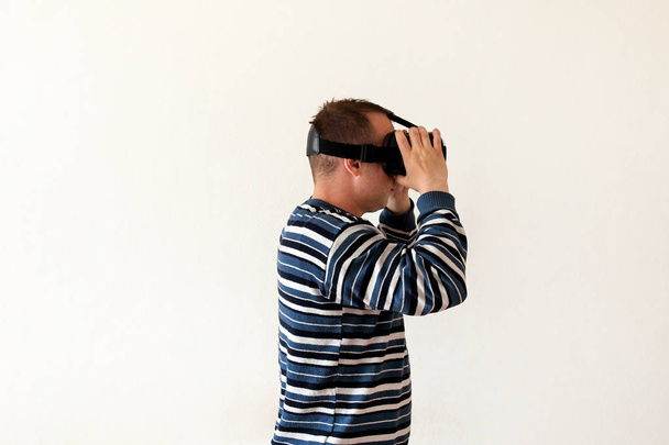 Homme portant et jouant application de jeu mobile sur l'appareil lunettes de réalité virtuelle sur fond blanc. Action de l'homme et en utilisant dans un casque virtuel, boîte VR pour une utilisation avec téléphone intelligent. Concept de technologie contemporaine
 - Photo, image