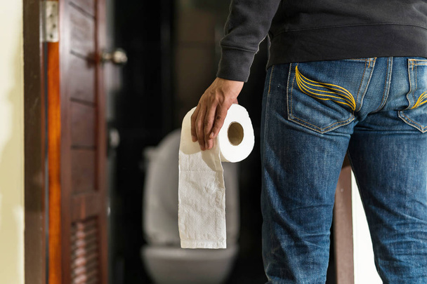Чоловік тримає рулон тканини в туалеті
 - Фото, зображення