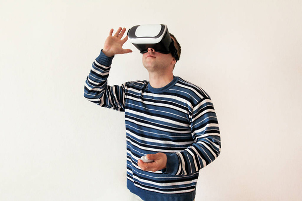 Man wearing and playing mobile game app on device virtual reality glasses on white background. Man action and using in virtual headset, VR box for use with smart phone. Contemporary technology concept - Foto, afbeelding