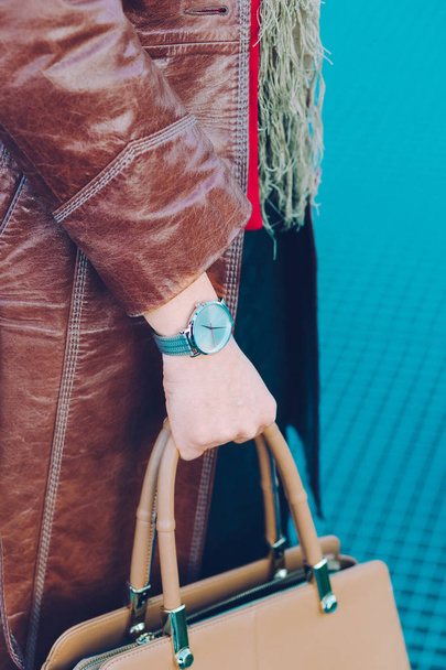 Woman wearing silver wristwatch and brown leather coat holding l - Foto, Bild