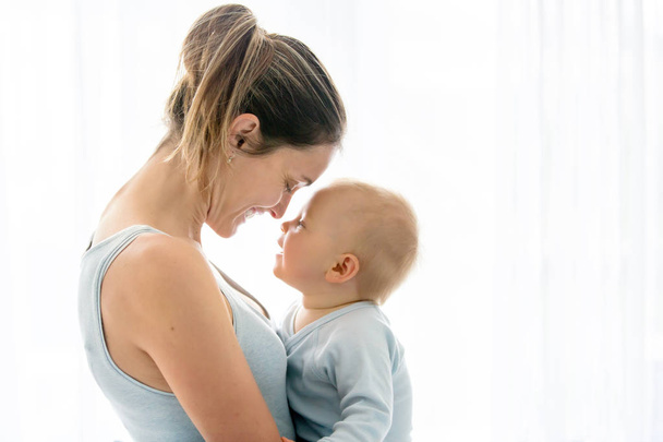 Young mother, embracing with tenderness and care her baby boy, s - Foto, Bild