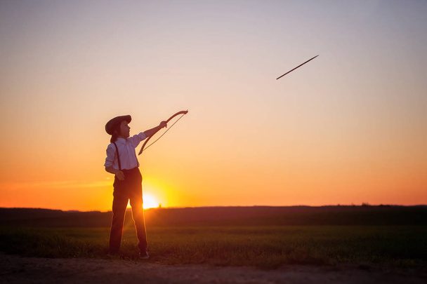 Силуэт ребенка, играющего с луком и стрелами, стрельба из лука
  - Фото, изображение