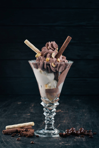 Chocolate ice cream with nuts. On a black wooden background. Copy space. - Фото, зображення
