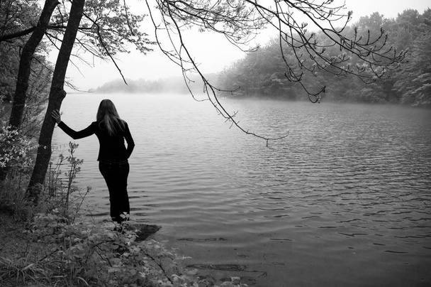 Silhouette of a girl contemplating a relaxed lake and meditating - Photo, Image