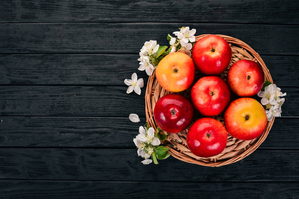 Φρέσκα κόκκινα μήλα με άνθη και φύλλα. Σε ένα ξύλινο υπόβαθρο. Το Top view. Χώρο αντίγραφο. - Φωτογραφία, εικόνα