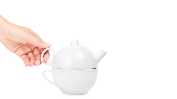white ceramic kettle or teapot with cup in hand. Isolated on white background. copy space, template - Foto, afbeelding