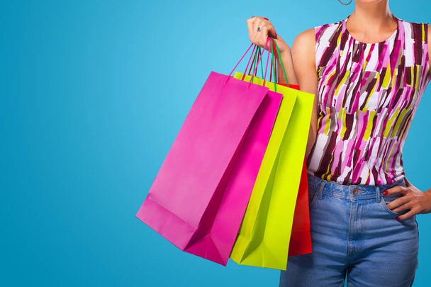 Shopping woman holding color bags isolated on blue background in black friday holiday. Summer sale concept. - Photo, Image