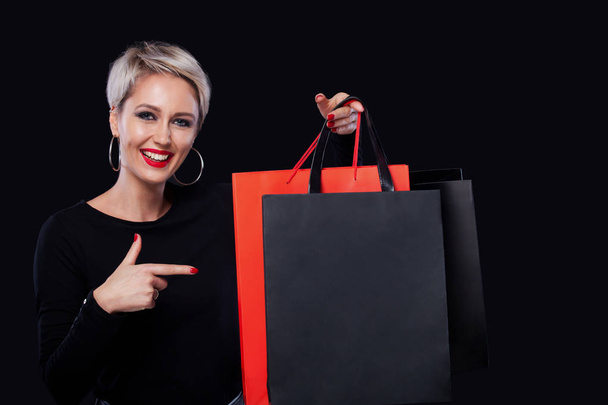 Shopping-Frau mit Farbbeuteln isoliert auf blauem Hintergrund in schwarz Freitag Urlaub. Sommerschlussverkauf. - Foto, Bild