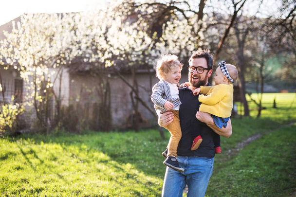 Un père avec des enfants en bas âge à l'extérieur au printemps nature
. - Photo, image