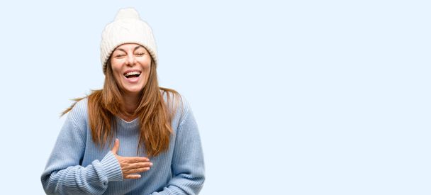 Keski-ikäinen nainen yllään villa talvi korkki luottavainen ja onnellinen iso luonnollinen hymy nauraa eristetty sininen tausta
 - Valokuva, kuva
