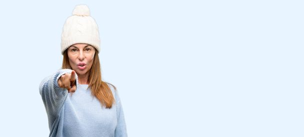 Middle age woman wearing wool winter cap pointing to the front with finger isolated blue background - Foto, immagini