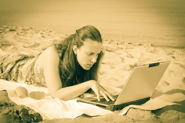 Donna che lavora al computer sulla spiaggia
 - Foto, immagini