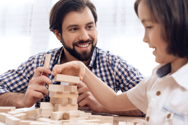 Adult father with small son plays Jenga at home. - Φωτογραφία, εικόνα
