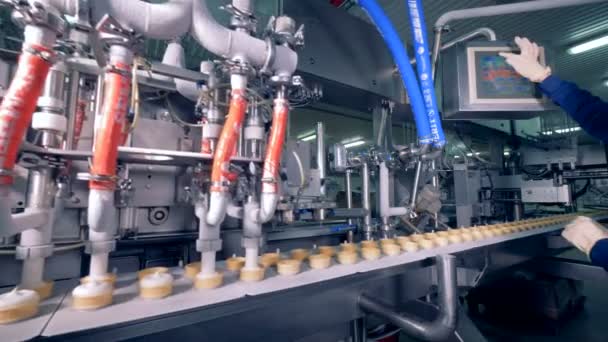 Przemysłowe maszyny jest wypełnienie wafel kubki z białe lody, podczas gdy pracownik fabryki jest ustawienie parametrów - Materiał filmowy, wideo