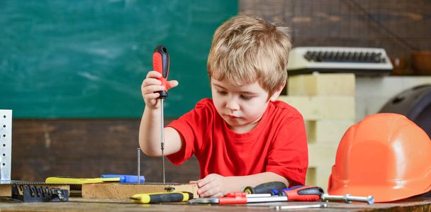 Kid learning to use screwdriver. Concentrated kid working in repairs workshop. Future occupation concept - Φωτογραφία, εικόνα