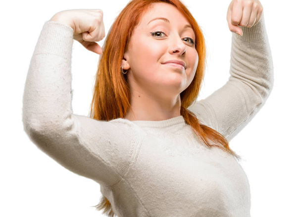 Piękne młode Rude kobiety wyświetlone biceps wyrażając koncepcja siły i siłowni, zdrowego życia jego dobry na białym tle nad białym tle - Zdjęcie, obraz