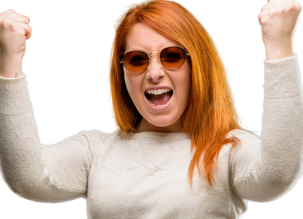 Beautiful young redhead woman happy and excited celebrating victory expressing big success, power, energy and positive emotions. Celebrates new job joyful isolated over white background - Fotoğraf, Görsel
