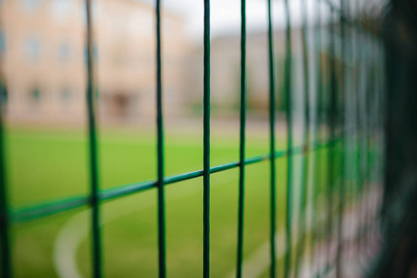 Cerca de la cerca verde metálica en forma de red sobre un fondo de campo de fútbol
 - Foto, imagen
