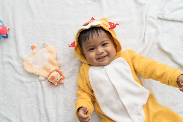 lindo poco asiático bebé mintiendo en manta y sonrisa
 - Foto, Imagen