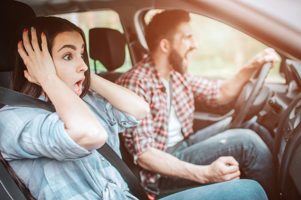 Mad guy and amazed girl are stopping unexpectedly. Guy is screaming while girl is holding her hands near ears and looking on road. - Foto, Bild