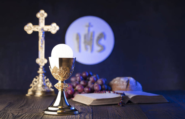 Eerste heilige communie thema. Het Kruis, Heilige Bijbel, rozenkrans en gouden kelk. Brood en druiven symbolen van het christendom. - Foto, afbeelding
